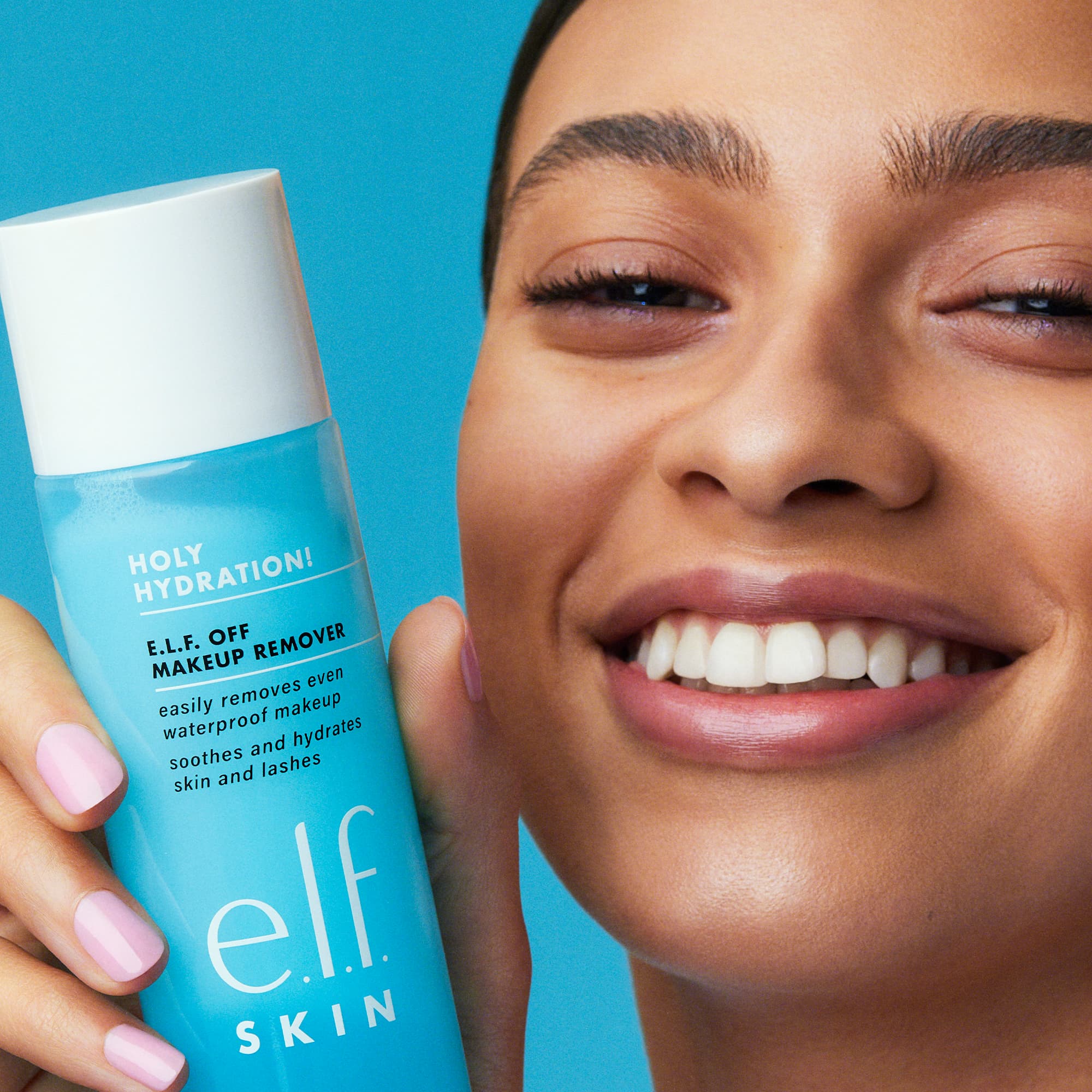 a smiling woman holding up an e.l.f. skin product