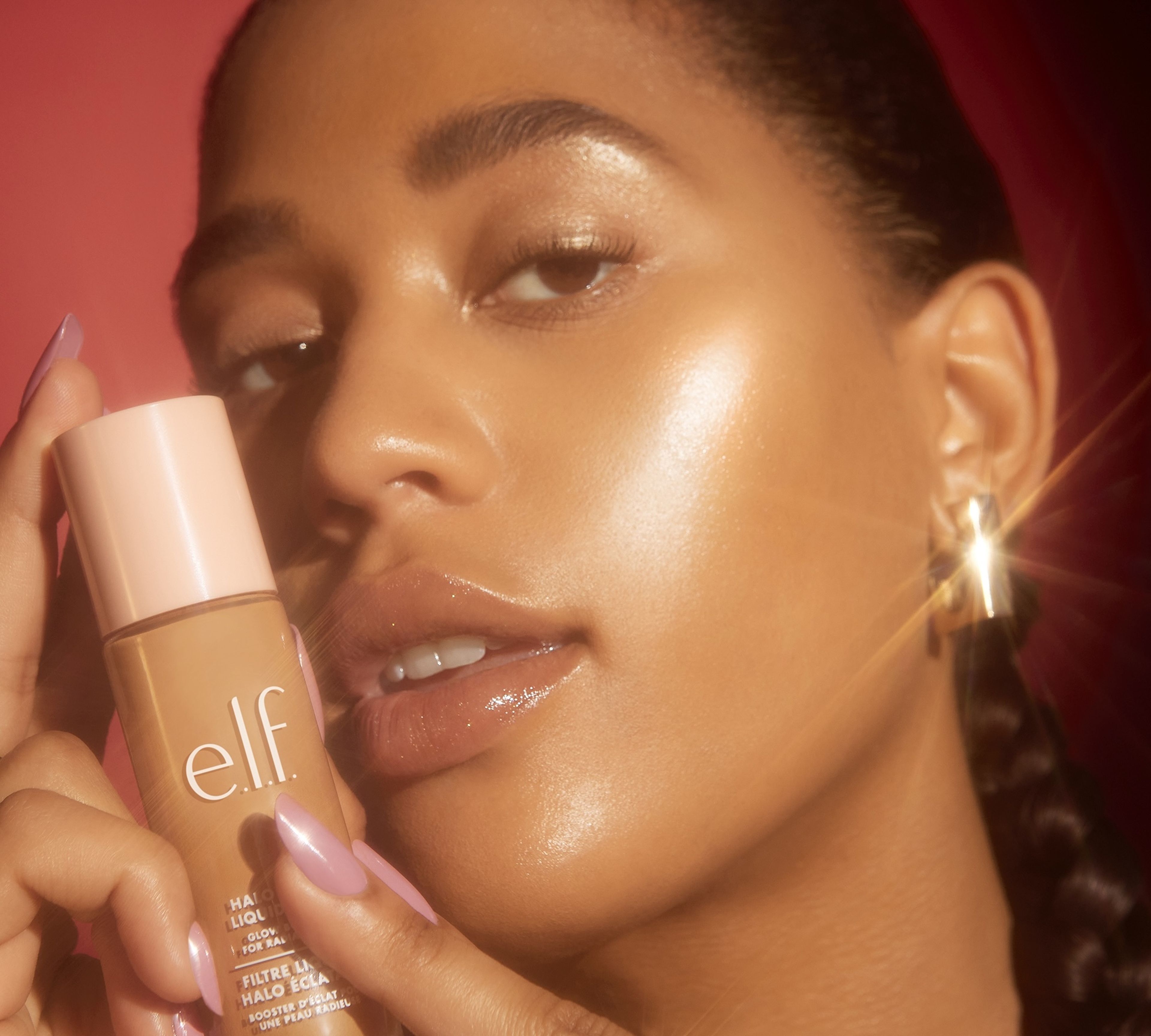a woman with smooth glowing skin holding elf product