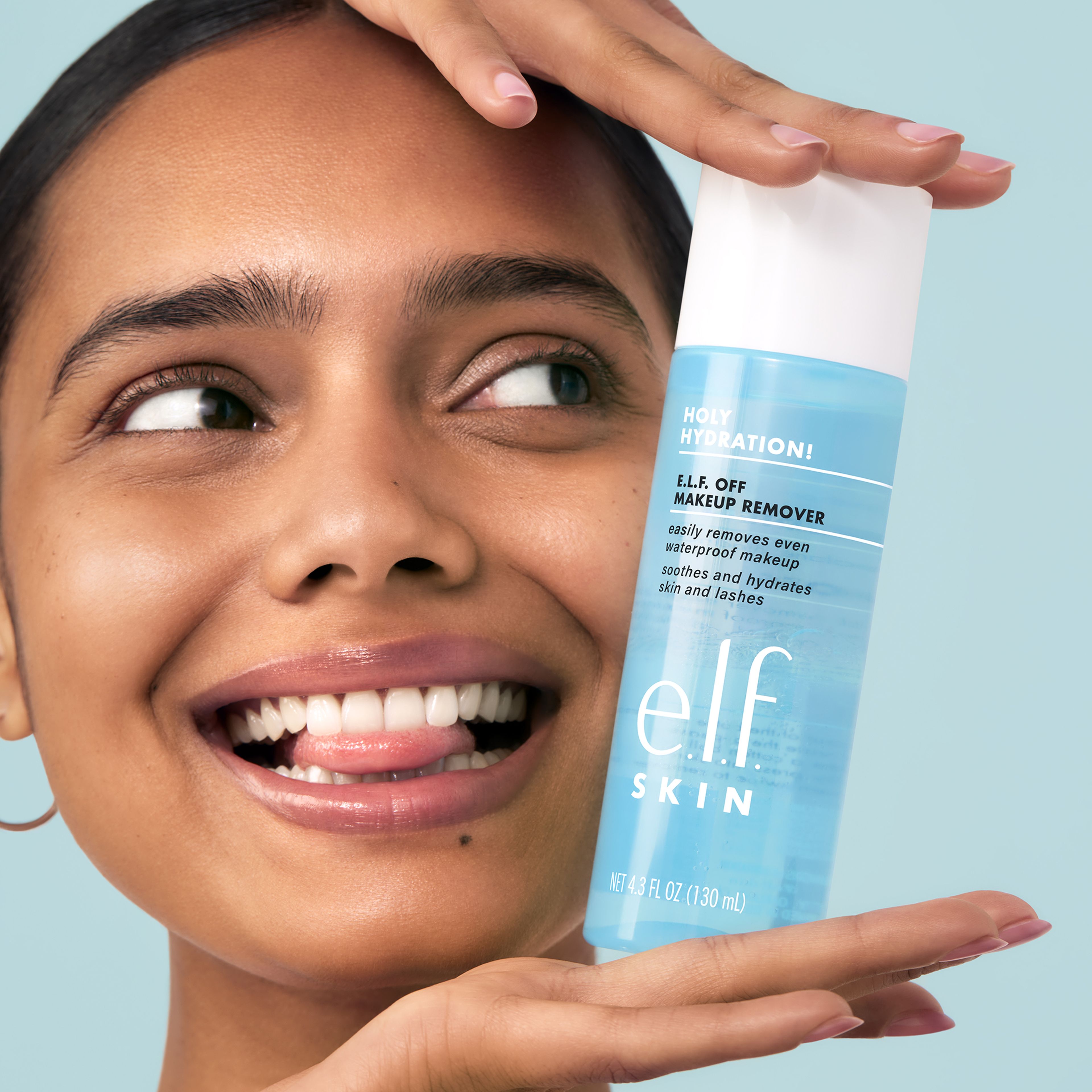 woman smiling biting her tongue holding elf skin product